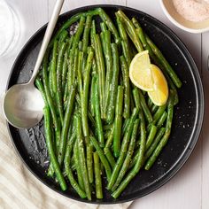 asparagus and lemon in a skillet on a white wooden table with other dishes