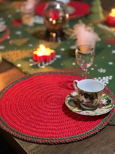 a place mat with a coffee cup and saucer on it next to a lit candle