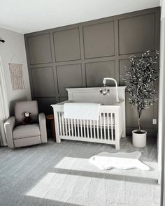 a baby's room with a crib, chair and potted plant