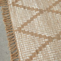 a brown and white rug with fringes on the ground next to a cement floor