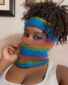 a woman with dreadlocks wearing a multicolored crocheted neck gaiter