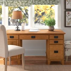 a desk with two chairs and a lamp in front of it, next to a window