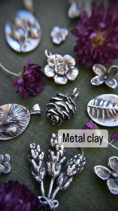 several metal clay flowers and leaves on a green surface with the words metal clay above them