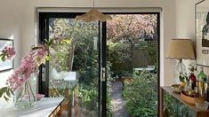 a room that has some flowers in vases on the table and an open door