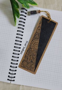 an open notebook with a wooden bookmark on it and a plant next to it