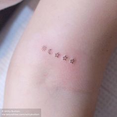 a woman's arm with three small stars and crescent moon tattoos on the left side