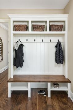 a white bench with two coats hanging on it and some shoes under the coat rack