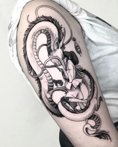 a black and white photo of a dragon tattoo on the left upper half of the arm