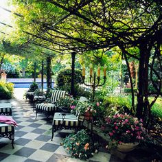 an outdoor seating area with black and white checkered tile on the floor, surrounded by greenery