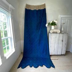 a large blue blanket sitting on top of a wooden floor next to a white dresser