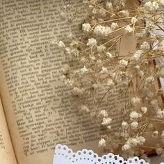 an open book with lace on it next to flowers