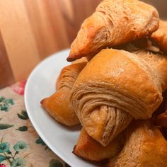 several croissants piled on top of each other on a white plate with floral table cloth