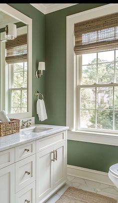 a bathroom with green walls and white cabinets