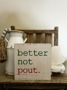 a wooden sign sitting on top of a table next to a white jug and some other items