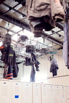 there are many jackets hanging on the rack in front of lockers with fireman's gear