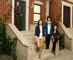 four people standing on steps in front of a house