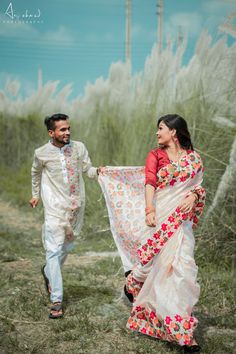 a man and woman are walking through the grass holding each other's scarves