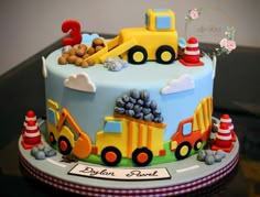 a birthday cake decorated with construction vehicles and traffic cones