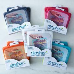 six stasher storage bags are shown in different colors and designs, with one holding the other's hand