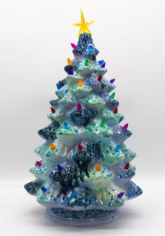 a glass christmas tree with multicolored lights on it's top and bottom