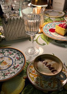 a table topped with plates and cups filled with desserts next to wine glasses on top of a table