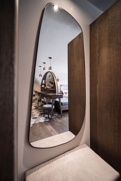 the reflection of a dining room table and chairs in a large, oval shaped mirror