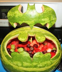 a watermelon carved to look like a bat with fruit in it's mouth