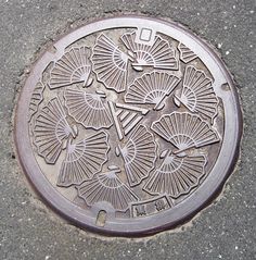 a manhole cover on the ground with umbrellas and flowers drawn on it's sides