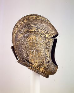 an old helmet is on display in a white room with a white wall behind it