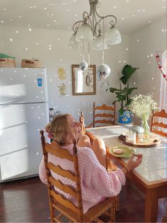 a woman sitting at a kitchen table in front of an icebox freezer and refrigerator