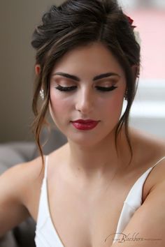 a woman with long hair wearing a white dress and red lipstick on her lips is looking down