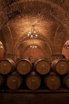 several wine barrels are lined up in an old brick cellar with chandeliers hanging from the ceiling