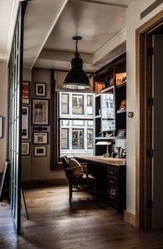 an office with wooden floors and lots of bookshelves in front of a window