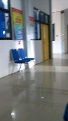 an empty hallway with blue chairs and posters on the wall in front of it's doors