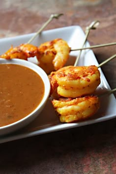 some food is sitting on a plate with toothpicks sticking out of it and dipping sauce in the bowl