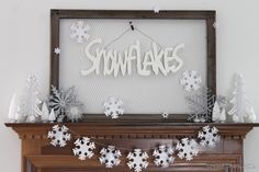 snowflakes are hanging on the mantle in front of a sign that reads, snowflakes