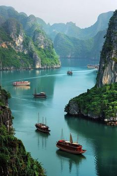 several boats floating on the water near mountains