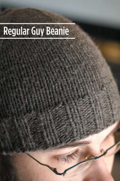 a man wearing glasses and a knitted beanie looks at his cell phone with the caption regular guy beanie