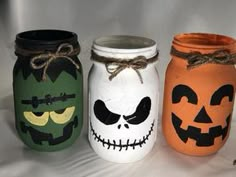 three painted mason jars decorated with halloween faces and jack - o'- lanternes