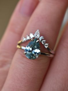 a woman's hand holding a blue and white diamond ring