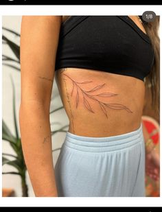 a woman's stomach with a leaf tattoo on her belly and the bottom half of her stomach