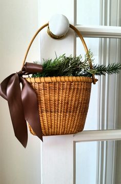 a wicker basket hanging on a door handle with a brown ribbon tied around it