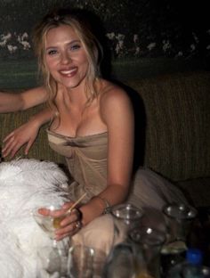 a woman sitting on top of a couch next to a table with glasses and drinks