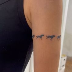 a woman's arm with three horses running across the line on her left side