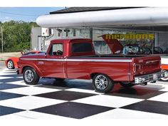 an old red pickup truck parked in front of a merrick's store on a checkered black and white floor