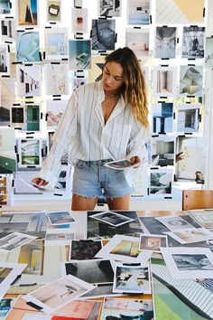 a woman standing in front of a table covered with pictures