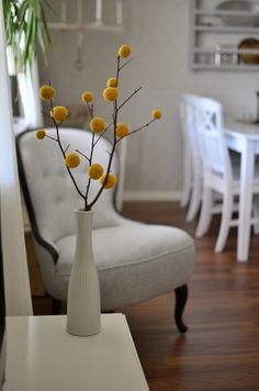 a vase filled with yellow flowers sitting on top of a table next to a white chair