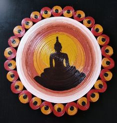 a plate with an image of a buddha in the center, surrounded by orange and yellow circles