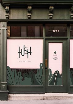 the front door of a flower shop with pink and green wallpaper on it's windows