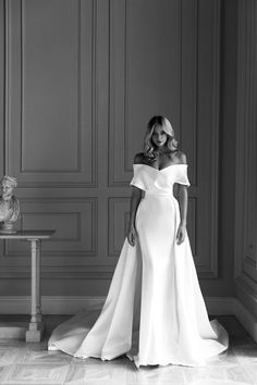 a woman in a white dress standing next to a table